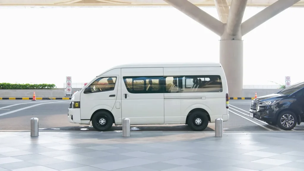 Monovolume bianco fermo nella corsia per la discesa dei passeggeri davanti a un terminal aeroportuale, da scegliere in base ai passeggeri del taxi alla Mecca