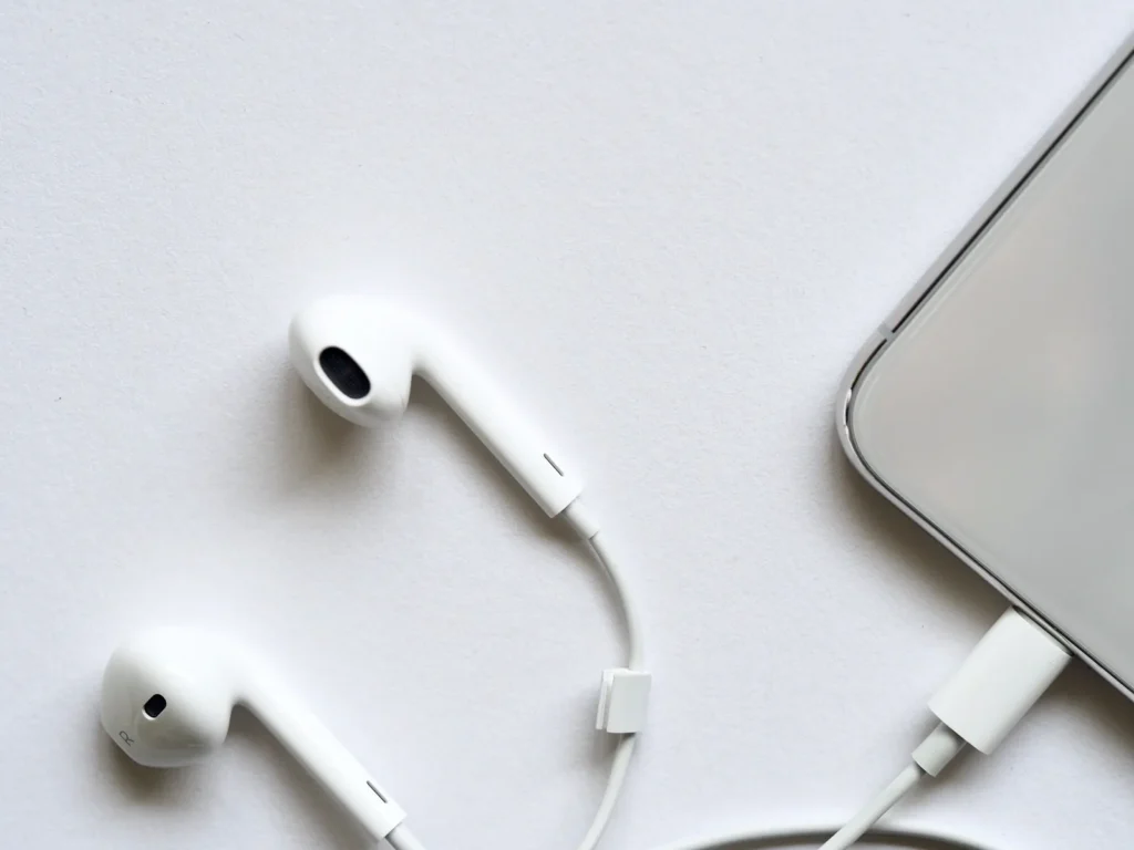 Auriculares blancos con cable y un teléfono parcialmente visible sobre una superficie clara, para seguir la traducción del sermón de la Gran Mezquita