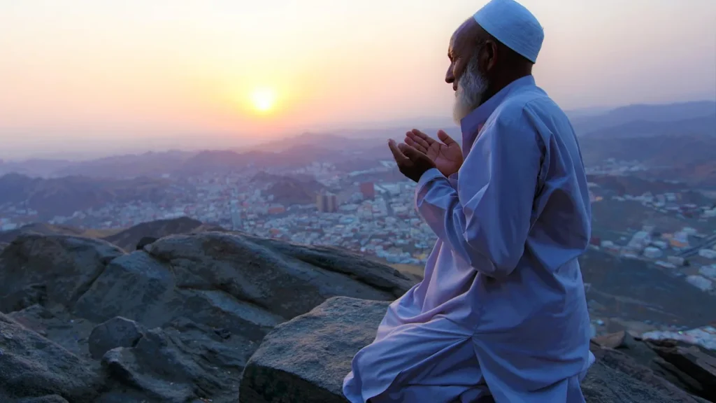 Uomo in preghiera su una sporgenza rocciosa di Jabal al-Nour al tramonto sopra la Mecca, vicino all'Hira Cultural District raggiungibile in taxi