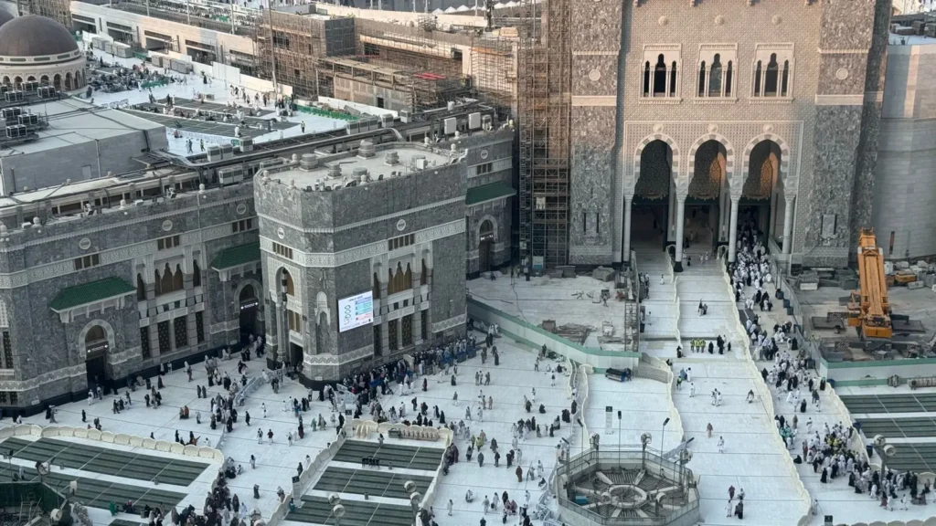 Blick von oben auf die Masjid al-Haram in Mekka mit Minaretten und belebtem Hof, unweit des Friedhofs Jannat al-Mualla