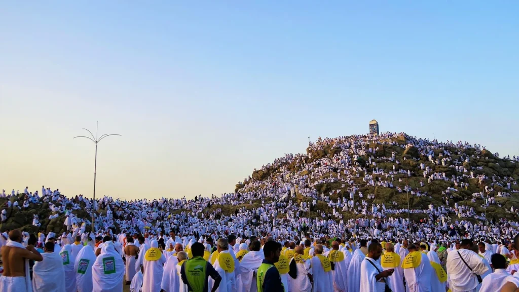 Pellegrini vestiti di bianco radunati sul Jabal al-Rahmah nella piana di Arafat, una visita per cui scegliere tra autista o guida turistica