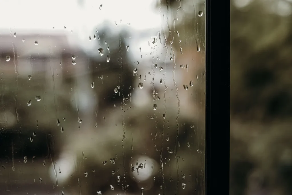 Regentropfen auf einer Fensterscheibe vor unscharfem Hintergrund, Symbolbild für eine Wetterwarnung in Mekka