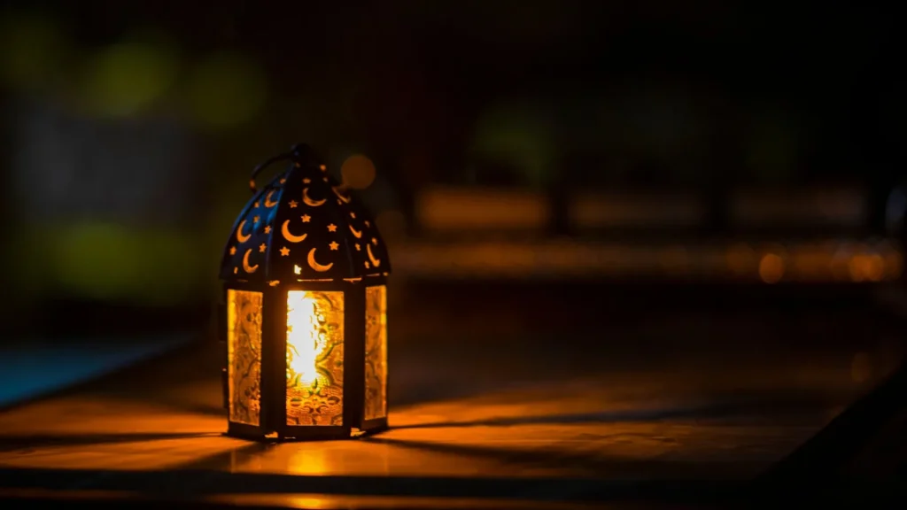 Lanterna con ritagli a forma di mezzaluna accesa in una stanza buia, immagine tipica di una ziyarah alla Mecca nel Ramadan