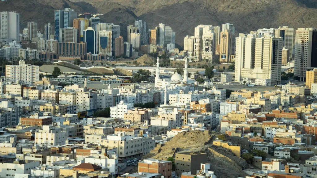 Stadtansicht von Mekka mit Hochhäusern und Bergen im Hintergrund, Rückweg nach dem Besuch der Masjid Aisha mit geänderter Abholzeit