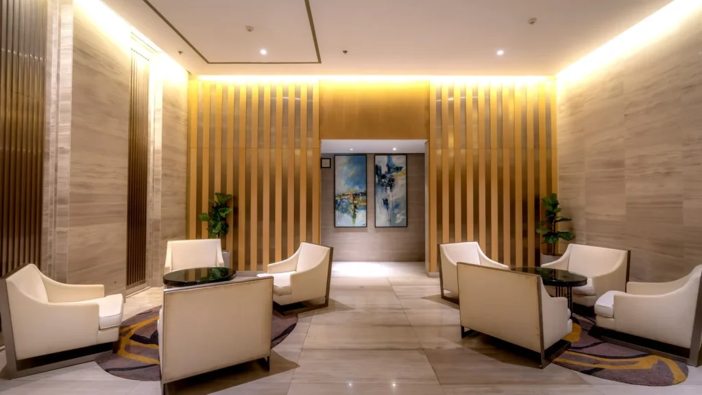 Salón de hotel tranquilo con sillones color crema y luz cálida en las paredes, lugar para quedar con familiares en otro hotel de La Meca