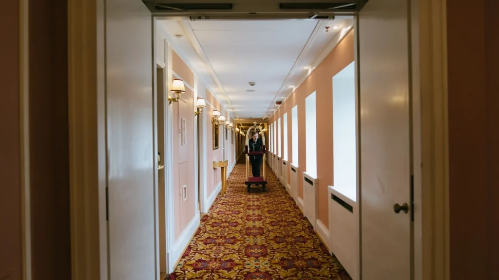 Hotelpage schiebt einen Gepäckwagen durch einen langen Hotelflur, typische Szene bei einem Hotelwechsel in Mekka mit dem Taxi