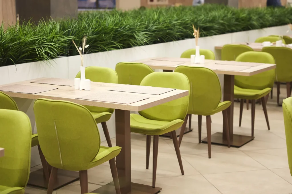 Grün gepolsterte Stühle an Holztischen mit Platzsets, Symbolbild für Restaurants in Mekka