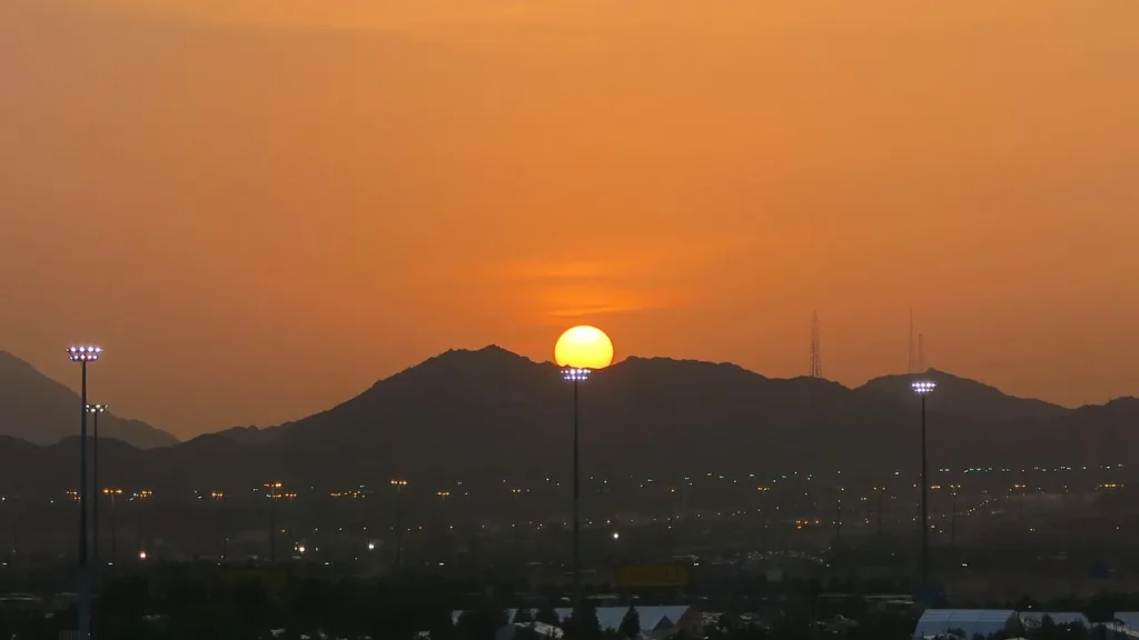 Il sole tramonta dietro le colline di Arafat, vicino alla Mecca, sulla pianura silenziosa: il paesaggio che vedi quando visiti Arafat fuori dall'Hajj