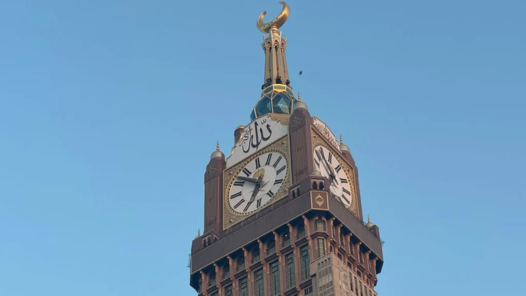 Quadrante della Torre dell'Orologio Abraj Al Bait alla Mecca contro il cielo azzurro, punto di riferimento per una ziyarah con arrivo in un altro hotel