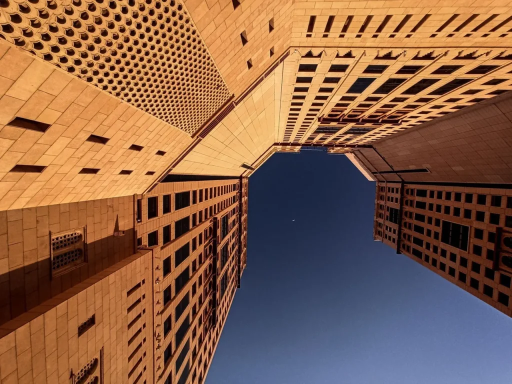 Looking up between high-rise buildings in Makkah against a clear sky